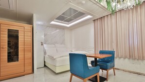 A modern bedroom with a bed, a wooden wardrobe, a table with chairs, and a skylight. - Hotel February Dongdaegu (Daegu)