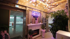 A hotel lobby with a fireplace, a neon sign, and wooden decor. - Hotel February Dongdaegu (Daegu)