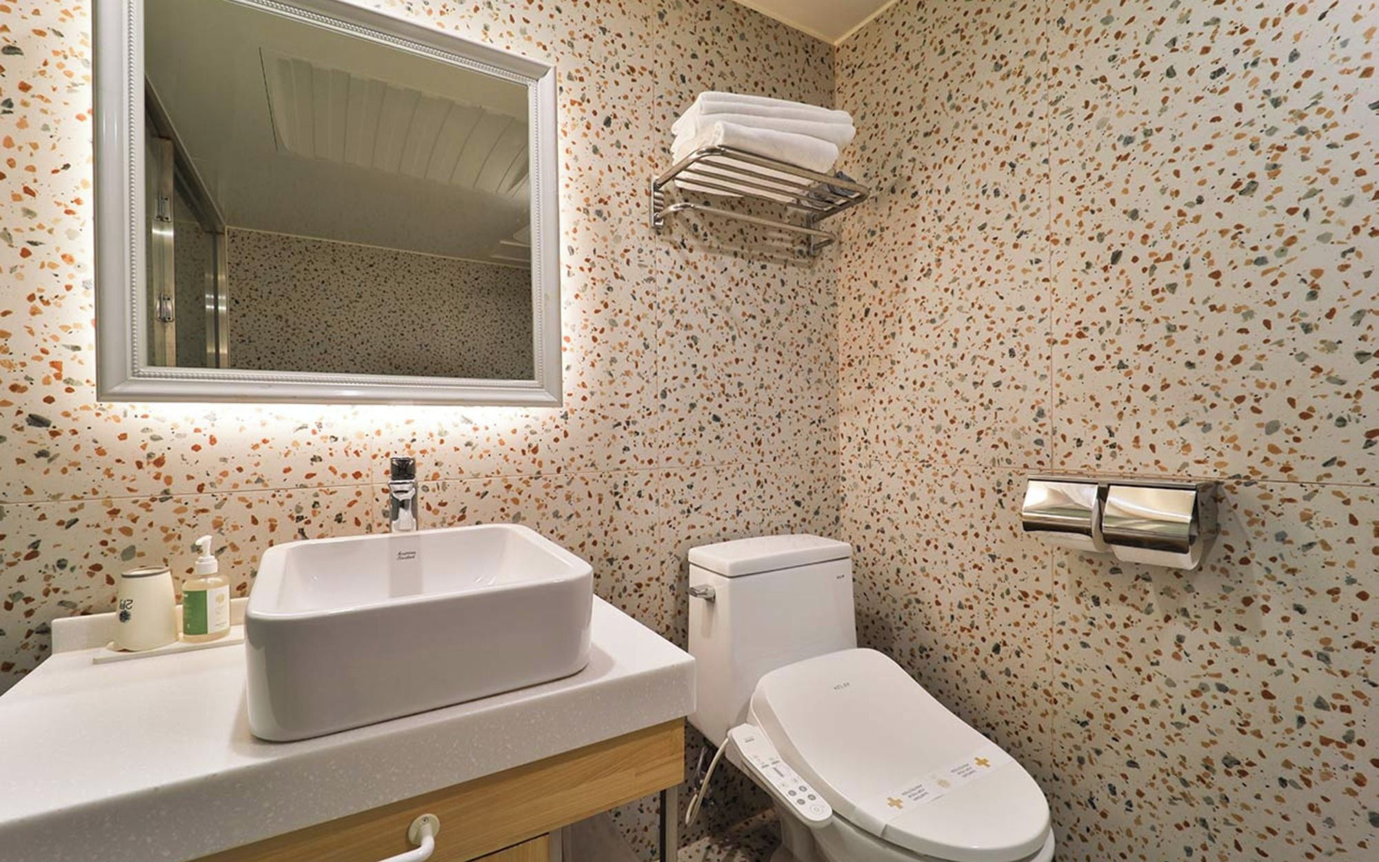 A bathroom with a freestanding sink, a toilet, a towel rack, and a mirror.