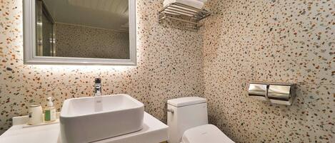 A bathroom with a freestanding sink, a toilet, a towel rack, and a mirror.