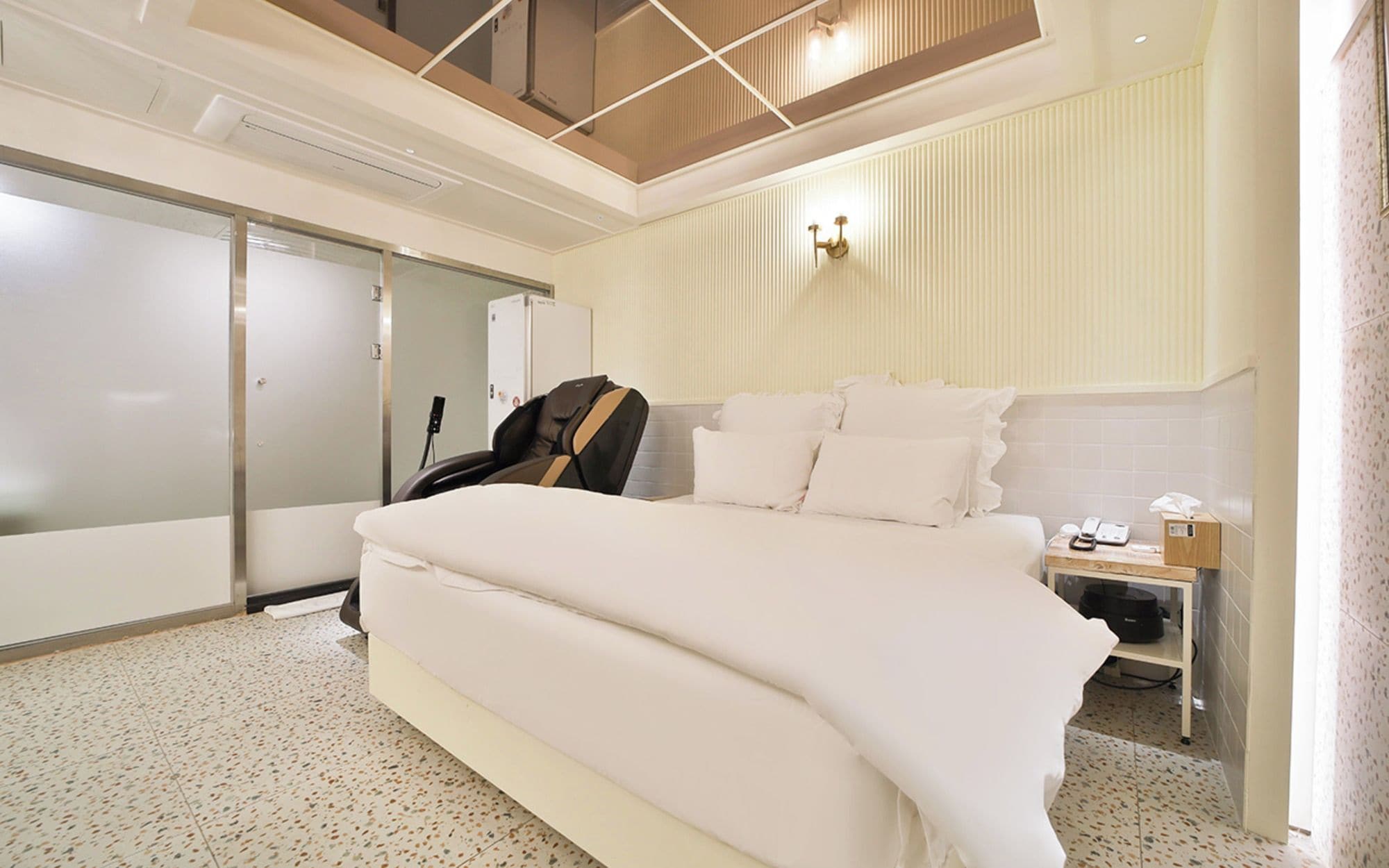 Une chambre d’hôtel moderne avec un grand lit, une armoire, un bureau avec un téléphone et un luminaire au plafond.