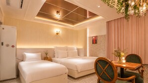 A hotel room with two beds, a dining table with chairs, a refrigerator, and a decorative chandelier. - Hotel February Dongdaegu (Daegu)