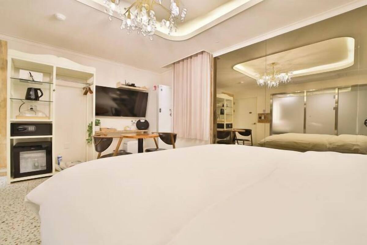 A modern hotel room with a large bed, a TV, a desk, and a wardrobe.