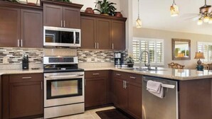 A modern kitchen with dark wood cabinets, stainless steel appliances, and a tiled backsplash.