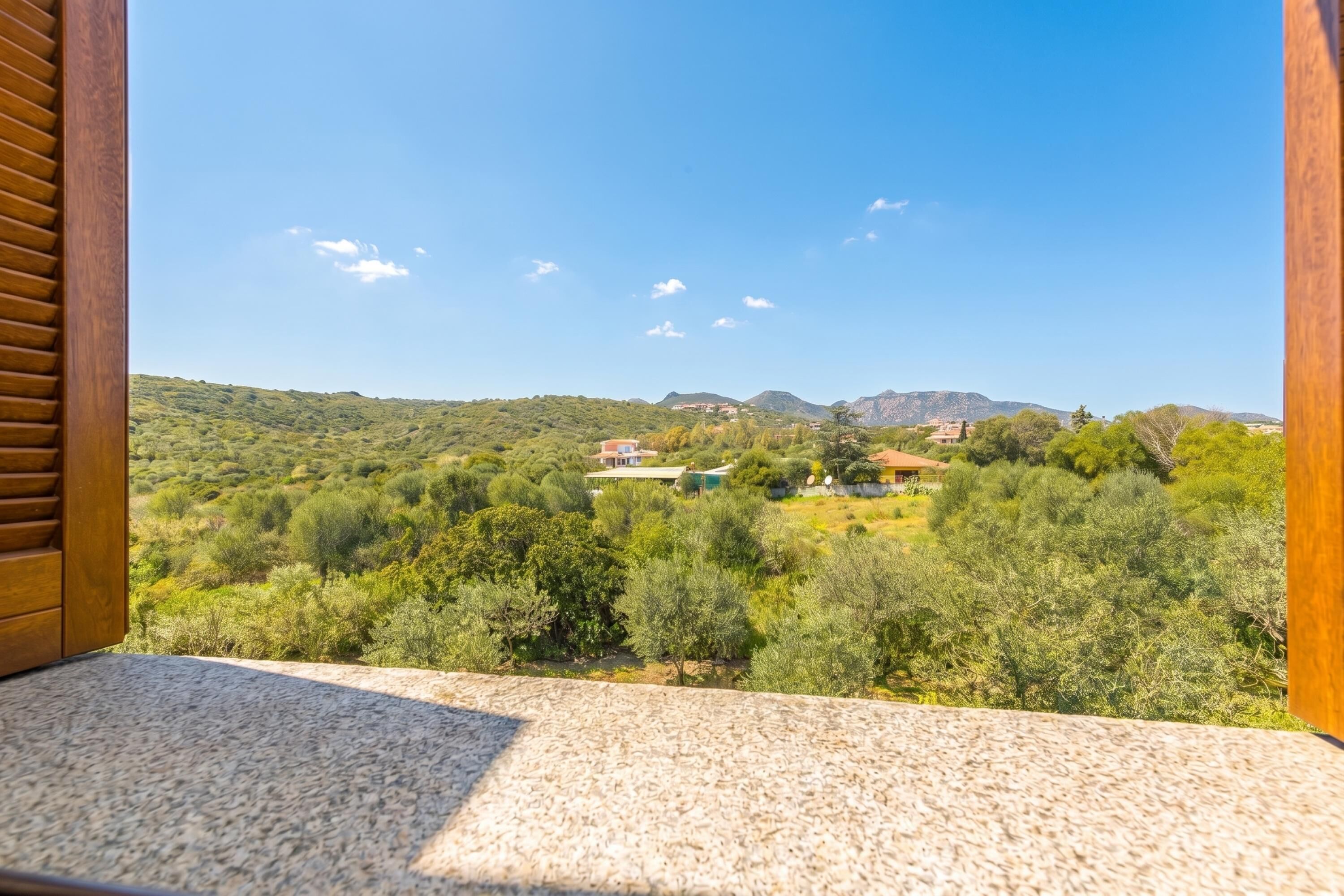 Un balcón con vistas a un paisaje verde y edificios a la distancia.