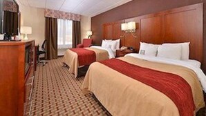 Une chambre d’hôtel avec deux lits, un bureau, une chaise et un téléviseur.