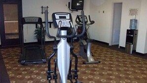 Une salle de sport équipée d’appareils de cardio et d’un distributeur d’eau.