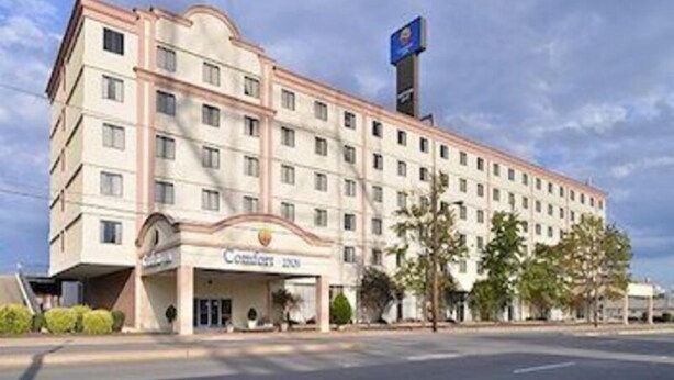 Un hôtel à plusieurs étages, reconnaissable à son enseigne bien visible indiquant « Comfort Inn ».