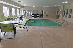 An indoor swimming pool with a tiled floor, surrounded by green chairs and tables. - Comfort Inn & Suites Ofallon - St Louis Area (O'Fallon)