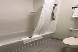 A bathroom with a bathtub, a shower curtain, a toilet, and a towel rack. - Comfort Inn & Suites Ofallon - St Louis Area (O'Fallon)