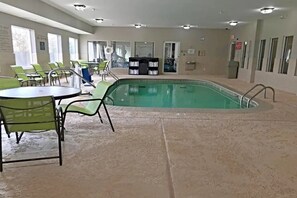 An indoor swimming pool with green chairs and tables, a changing room, and a reception desk. - Comfort Inn & Suites Ofallon - St Louis Area (O'Fallon)