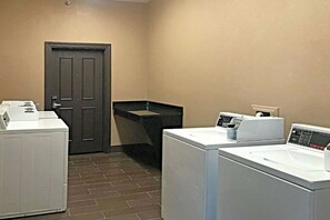 A laundry room with two washing machines, a dryer, and a door. - Comfort Inn & Suites Ofallon - St Louis Area (O'Fallon)