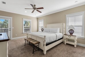 Ein Schlafzimmer mit einem weißen Bett, einer Holzbank, einem Nachttisch und einem Deckenventilator.