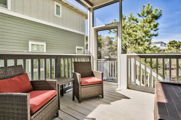 A covered outdoor deck with wicker furniture and a wooden table.