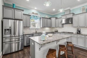 A modern kitchen with stainless steel appliances, a granite countertop island, and bar stools.