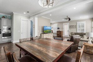 A spacious living area with a dining table, comfortable seating, a kitchen with modern appliances, and a large TV.