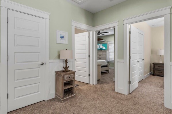 A hallway with white doors, a small wooden cabinet, and a ceiling fan.