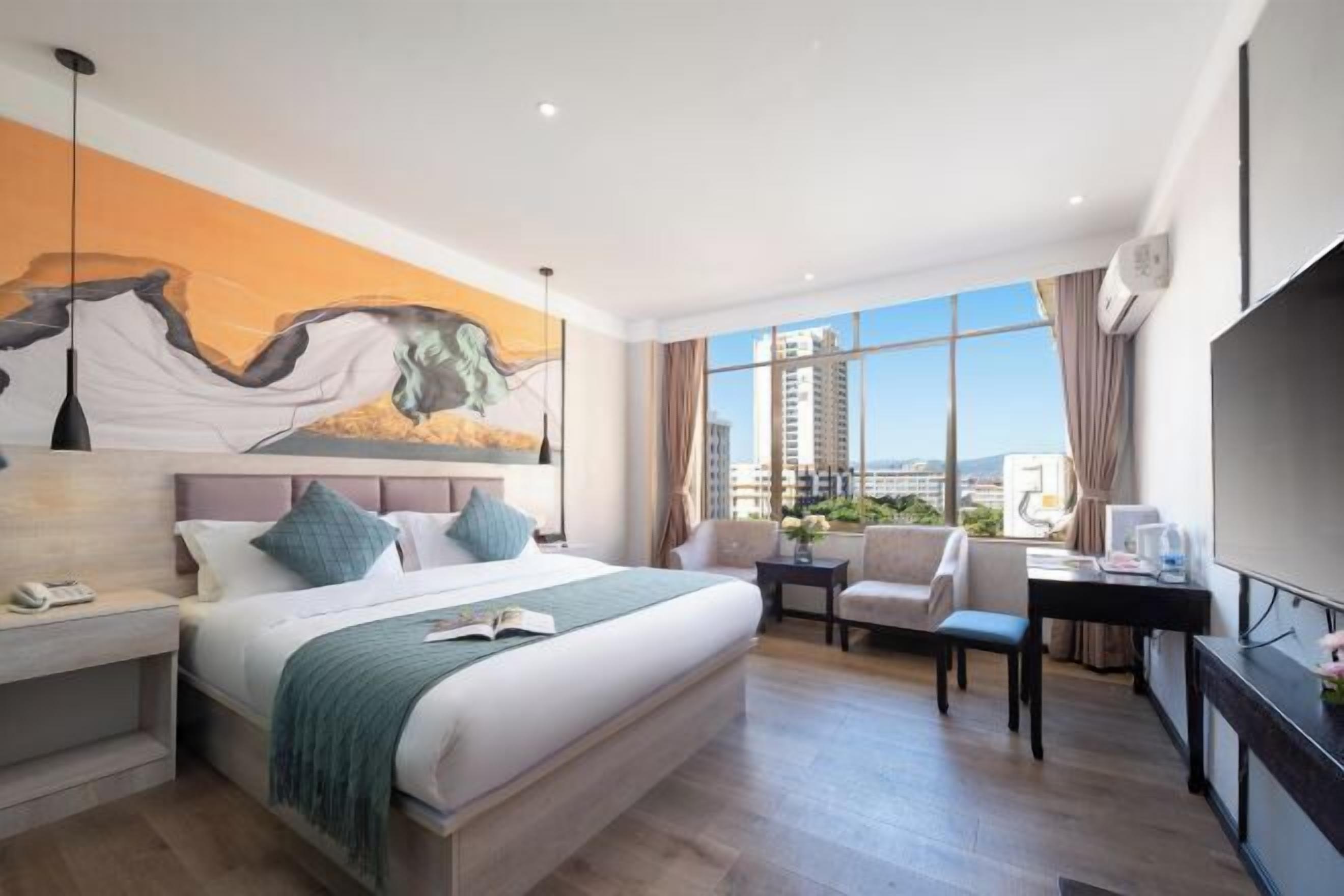 A modern hotel room with a large bed, a desk, a chair, and a TV.