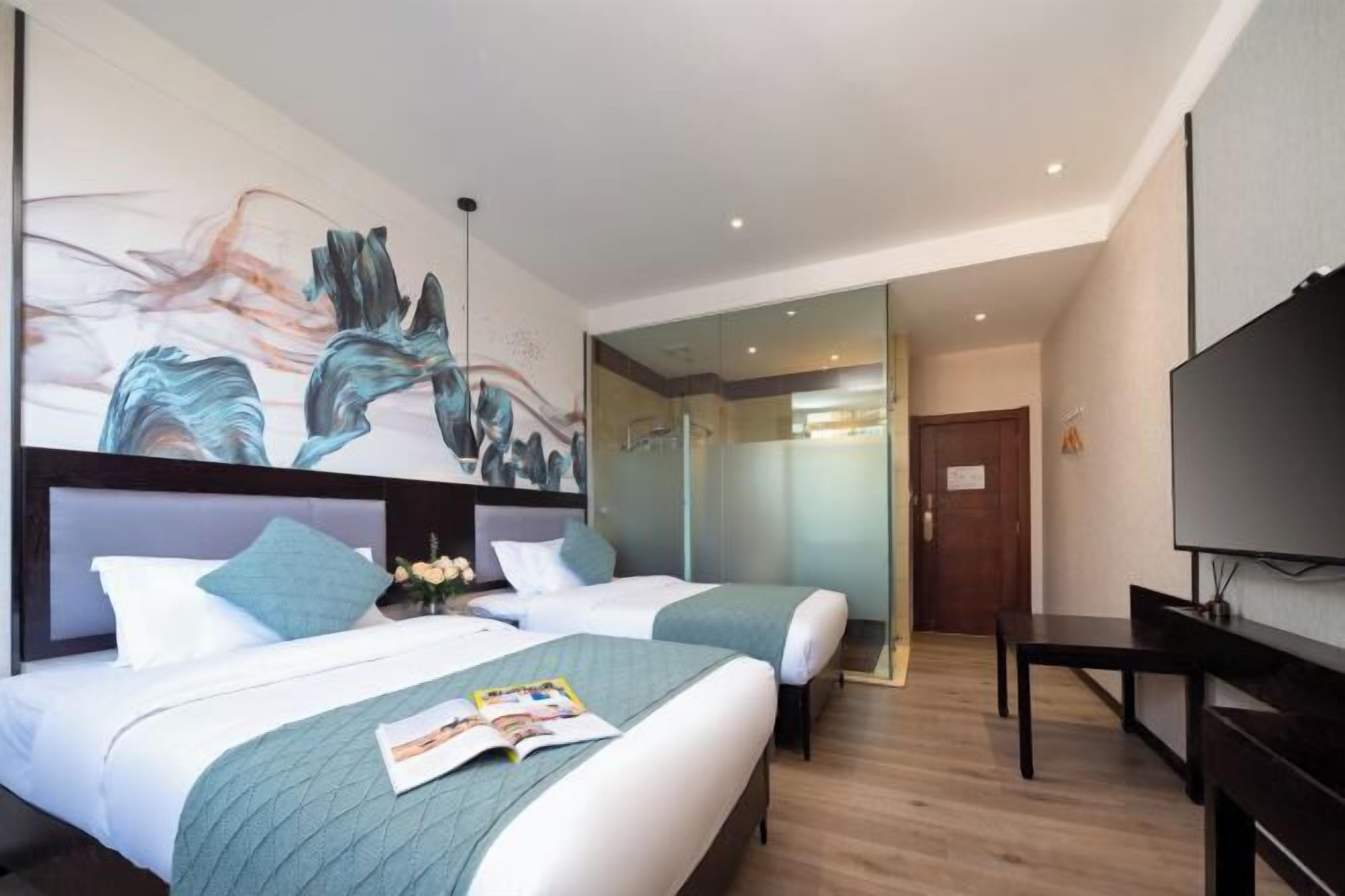 A hotel room with two beds, a large abstract painting on the wall, a television, and a wooden floor.