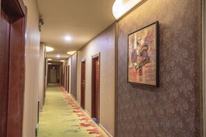 A hotel hallway with doors on both sides, a patterned carpet, and a framed artwork on the wall. - Moore Hotel Yuxi (Yuxi)
