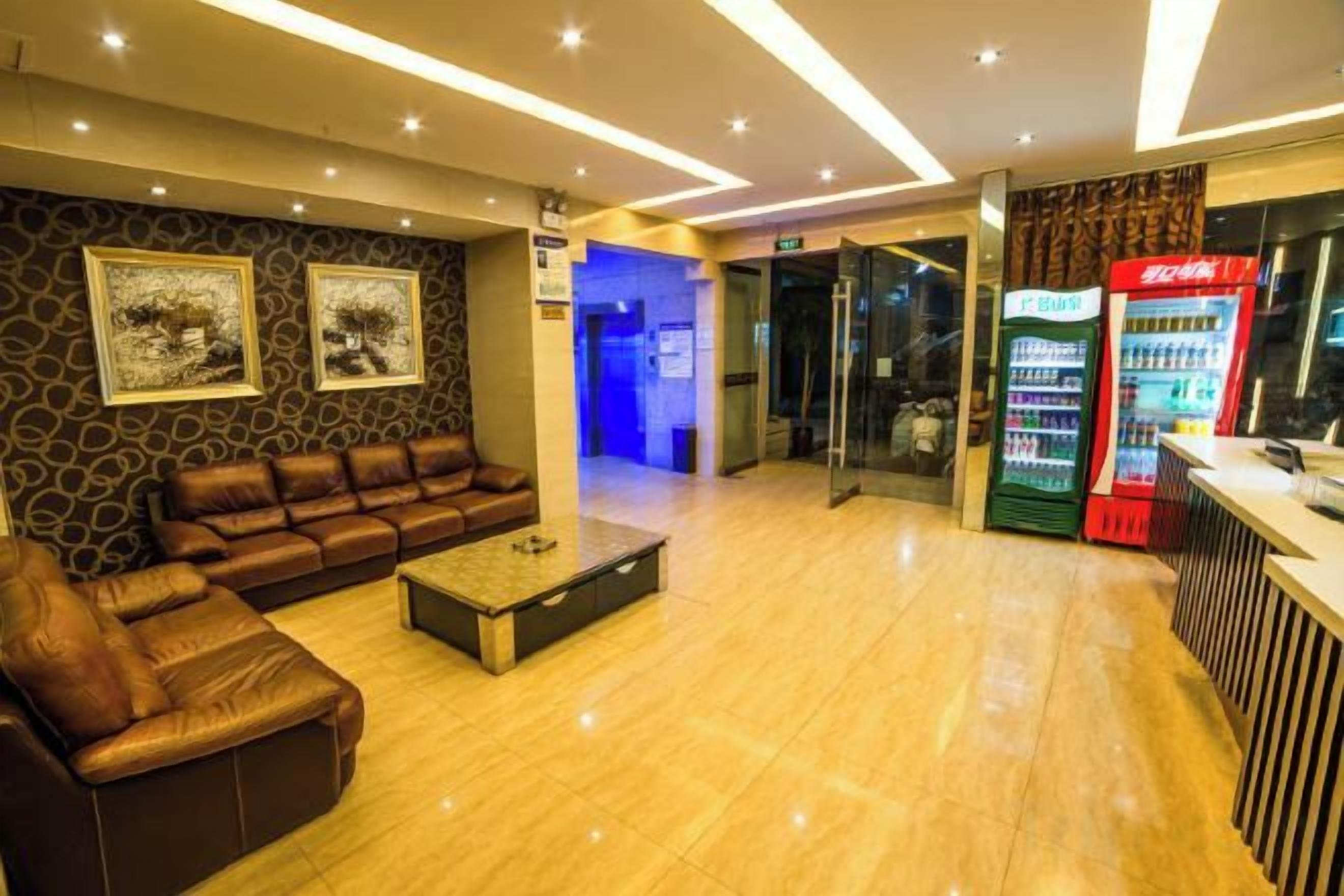 A hotel lobby with a leather sofa, a coffee table, a Coca-Cola vending machine, and a reception desk.
