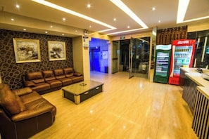 A hotel lobby with a leather sofa, a coffee table, a Coca-Cola vending machine, and a reception desk. - Moore Hotel Yuxi (Yuxi)
