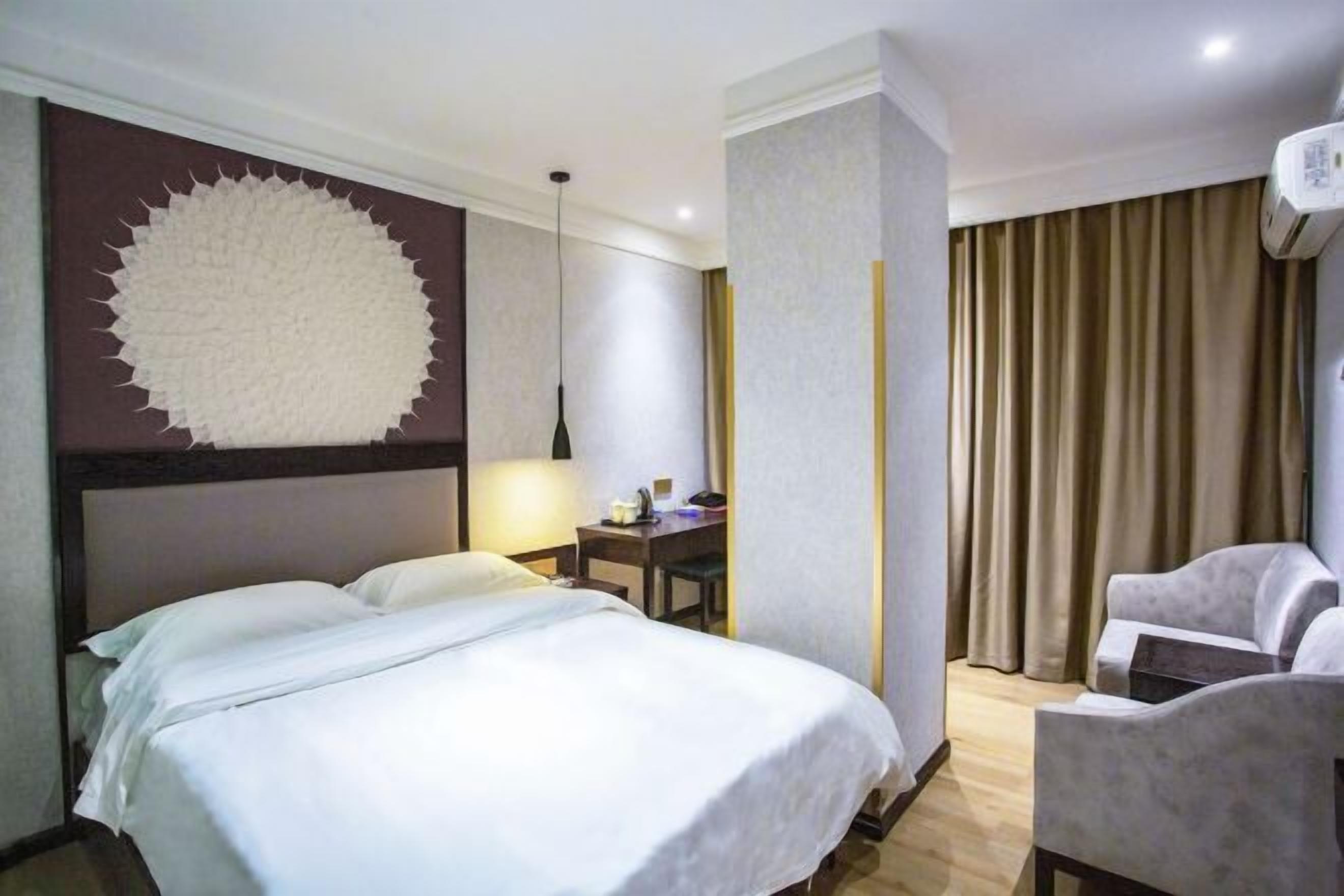 Una habitación de hotel con cama, escritorio, silla y un gran elemento decorativo en la pared.