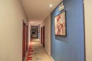 A hotel hallway with doors on both sides, a patterned carpet, and a framed artwork on the wall. - Moore Hotel Yuxi (Yuxi)