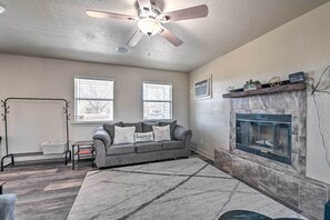 A living room with a gray sofa, a fireplace, and a ceiling fan. - Bright Brownwood Home with On-Site River Access! (Brownwood)