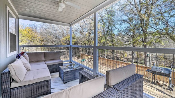A covered outdoor seating area with wicker furniture and a view of trees and a barbecue grill. - Bright Brownwood Home with On-Site River Access! (Brownwood)