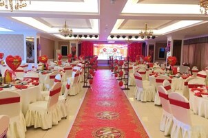 Un salón de banquetes con mesas redondas, sillas y alfombra roja.