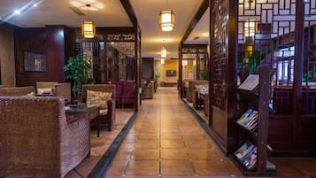 A corridor with wicker furniture, a bookshelf, and traditional decor.