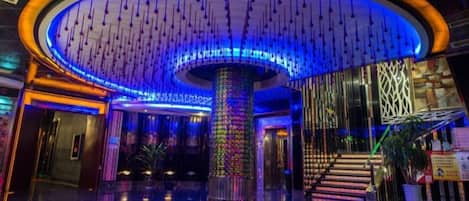 Eine Lobby mit einer zentralen Säule, einer Treppe und einem modernen Design.