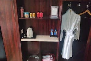A wooden wardrobe with shelves containing toiletries, a robe hanging on a hook, and a small basket.