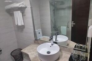 A bathroom with a sink, mirror, and shower.