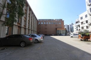 Un estacionamiento con varios autos, un edificio de varios pisos y un cielo despejado.