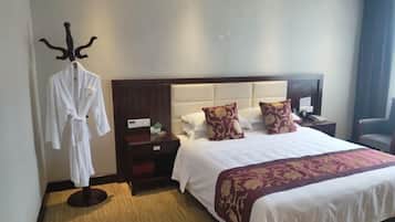 A hotel room with a large bed, a robe on a stand, a nightstand, and a chair.