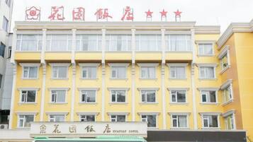 A hotel building with multiple floors, a signboard with hotel name, and a bus in front.