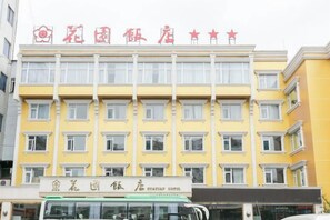 Un edificio de hotel con varios pisos, un cartel con el nombre del hotel y un autobús en la entrada.