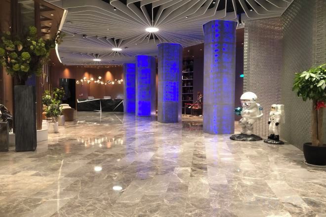A lobby with a marble floor, large columns, and a reception desk.