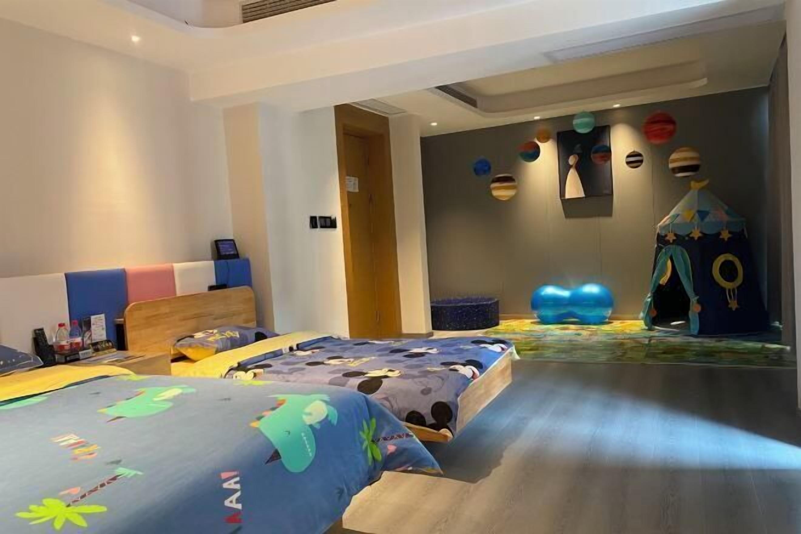 A hotel room with two beds, a large window, and a wall decorated with planetary models.