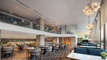 A spacious indoor area with multiple dining tables and chairs, a mezzanine level, and large windows providing natural light.