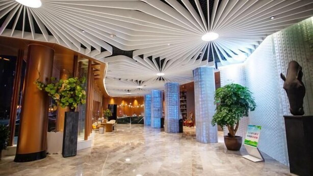 A modern hotel lobby with a high ceiling, marble flooring, and decorative lighting. - Greenman Lv Yijia Hotel (Poyang)