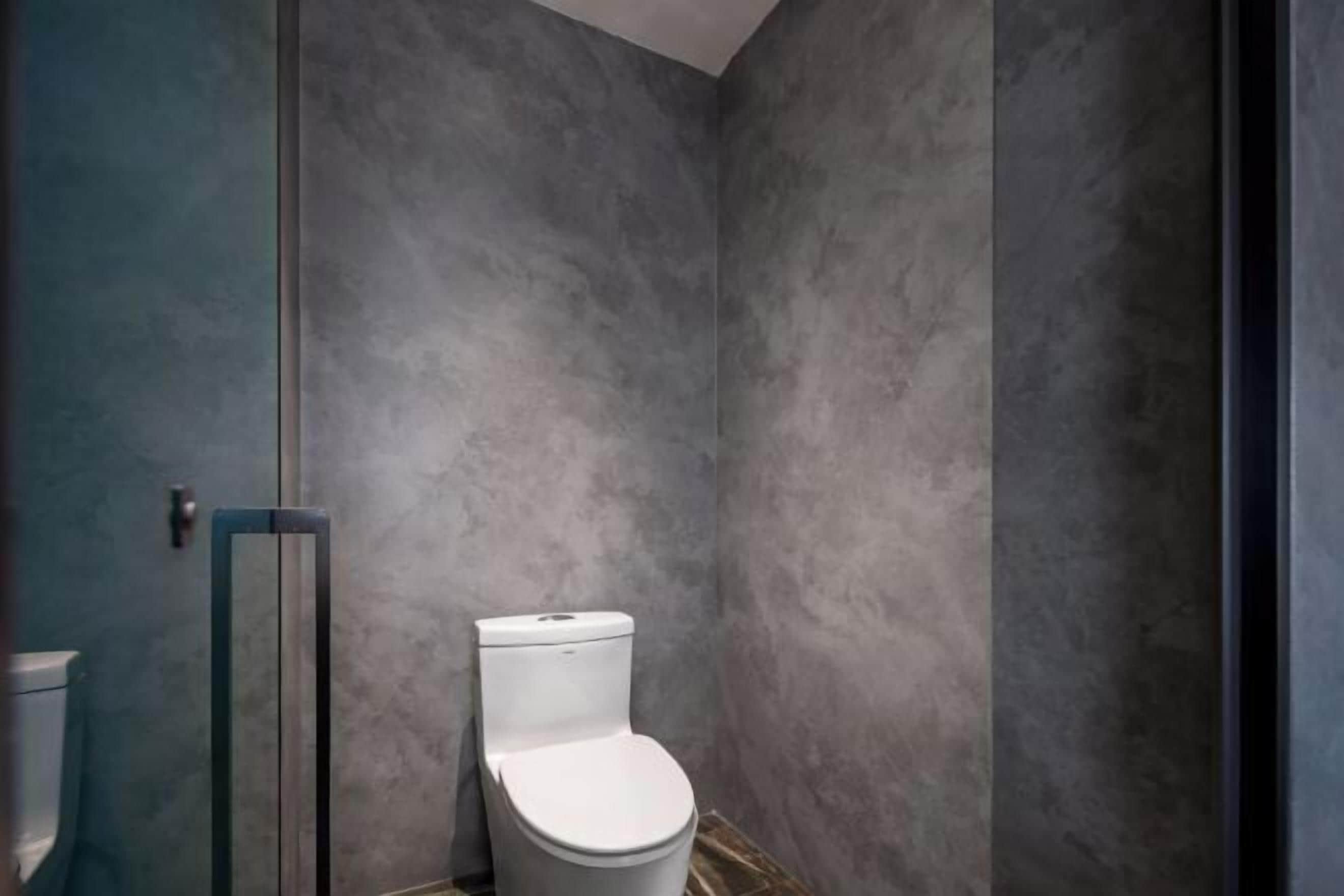 A bathroom with a white toilet, a glass shower enclosure, and a blue wall.