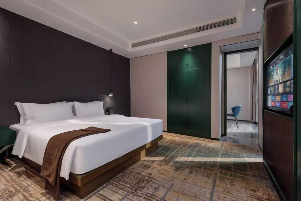 Ein modernes Hotelzimmer mit einem großen Bett, einer grünen Wand und Blick auf den Flur.