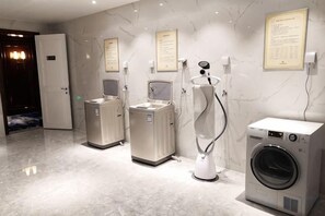 Un baño moderno con piso de mármol, lavadora y dos secadoras.