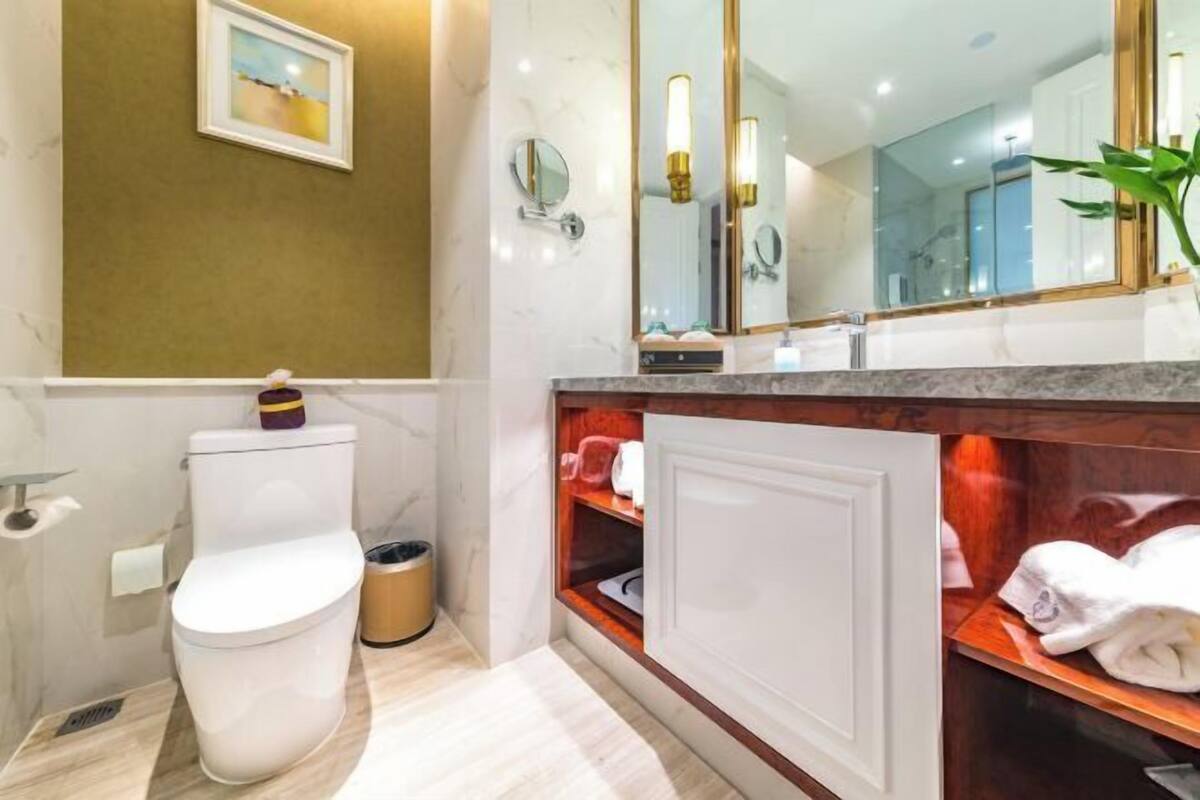 A modern bathroom with a toilet, a sink, a mirror, and a shower area.