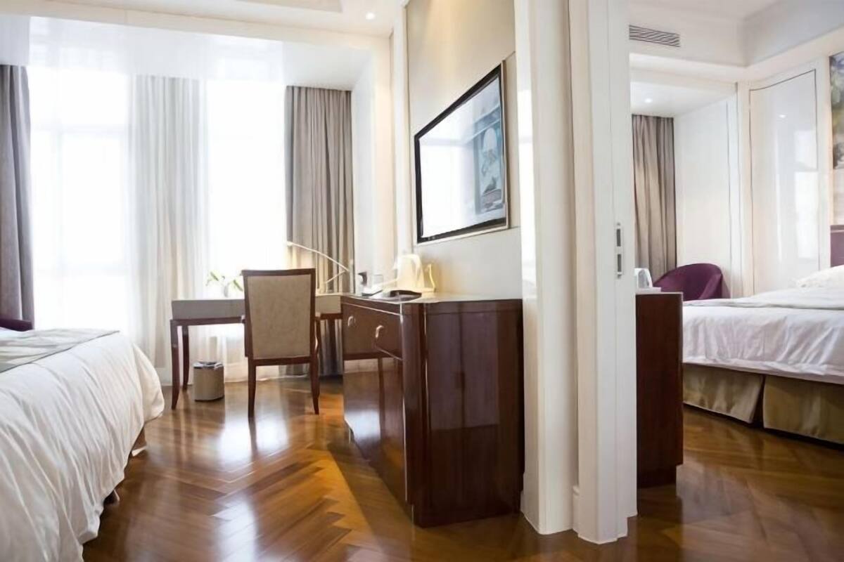 A hotel room with a bed, desk, chair, and a large window.