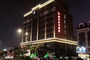 A multi-story hotel with illuminated exterior lighting, a prominent sign, and a parking lot with cars. - Greentree Eastern Hotel (Jianhu Ouba Liya Life Square) (Jianhu)