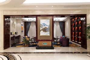 A hotel lobby with a reception desk, seating area, artwork, and a bookshelf. - Greentree Eastern Hotel (Jianhu Ouba Liya Life Square) (Jianhu)